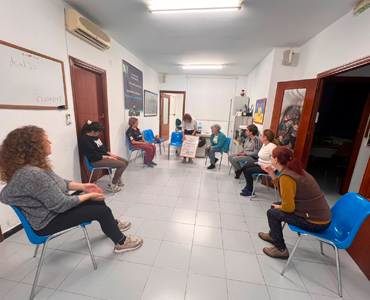 Grupo de personas alrededor de una mesa recibiendo apoyo para la intervención social.